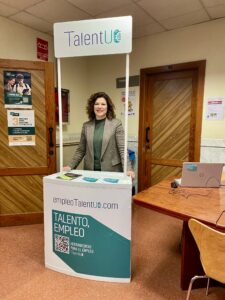 La técnica de Herramientas para el Empleo talentUO sonríe desde el stand informativo ubicado en el Hall de la Escuela